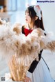 A woman in a white dress holding a bunch of pampas grass.