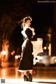 A woman in a black and white dress is walking down the street.