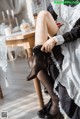 A woman in a maid outfit sitting on a chair.