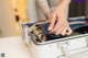 A person putting a piece of luggage in a suitcase.