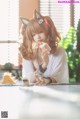 A woman sitting at a table with a cupcake in her hand.