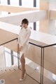 A woman in a white dress standing on a staircase.