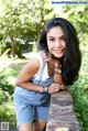 A woman leaning against a stone wall in a park.