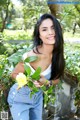 A woman holding a yellow flower in her hand.