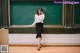 A woman standing in front of a blackboard talking on a cell phone.