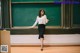 A woman standing in front of a blackboard in a classroom.