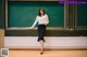 A woman standing in front of a blackboard in a classroom.