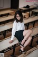 A woman sitting on a bench in a classroom.