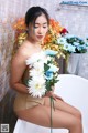 A woman sitting in a bathtub holding a bunch of flowers.