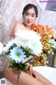 A woman sitting in a bathtub holding a bunch of flowers.