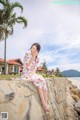 A woman in a white dress sitting on a stone wall.