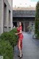 A woman in a red dress standing on a sidewalk.