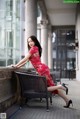 A woman in a red dress sitting on a chair.