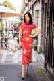 A woman in a red cheongsam poses for a picture.