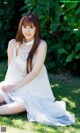 A woman in a white dress sitting on the grass.